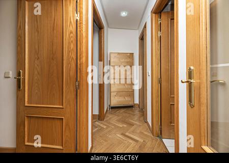 Ein schmaler, aber funktionaler Durchgang mit integriertem Garderobenständer, ordentlich unter einer Holzbank angeordneten Schuhen und einem kleinen Konsolentisch mit Anhänger Stockfoto
