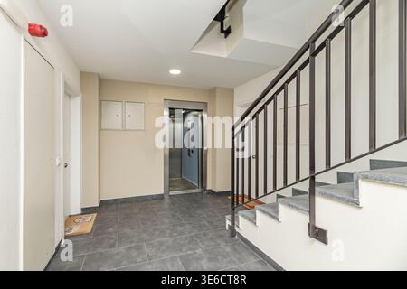Landung eines Gebäudes mit Treppen mit schwarzem Metallgeländer und modernem Aufzug Stockfoto