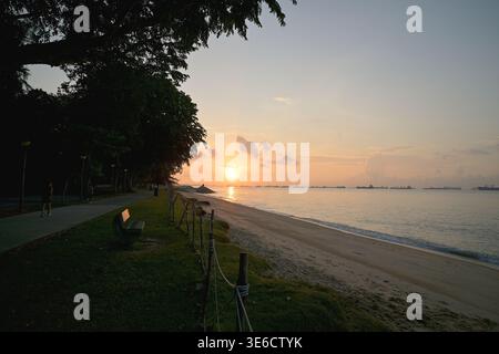 Der East Coast Park bietet flache und gepflasterte Routen, um am Strand entlang zu laufen und die malerische Aussicht auf die Straße von Singapur zu genießen, die hier bei Sonnenaufgang zu sehen ist Stockfoto