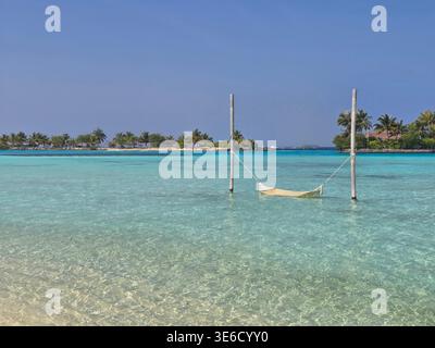 Tropisches Reiseziel zeigt an einem sonnigen Tag ruhiges Wasser und weiße Sandstrände zusammen mit Überwasser-Villen auf den Malediven. Stockfoto