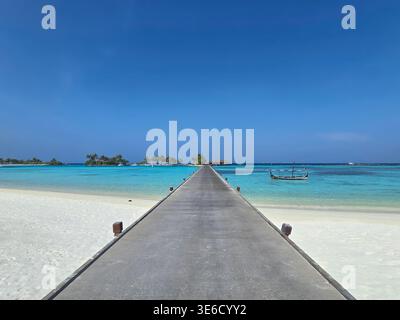 Der Fußweg führt zu Luxusvillen über klarem Wasser auf den Malediven. Weißer Sand und türkisfarbenes Meer sorgen für einen perfekten Inselurlaub. Stockfoto