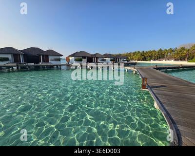 Klares türkisfarbenes Wasser umgibt die Villen in einem Luxusresort auf den Malediven und schafft so eine wunderschöne tropische Szene für Reisende. Stockfoto