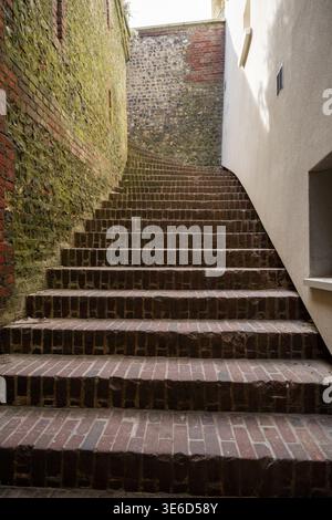 Eine schmale Backsteintreppe zwischen alten Mauern führt zu urbaner Architektur und historischem Gassenkonzept Stockfoto