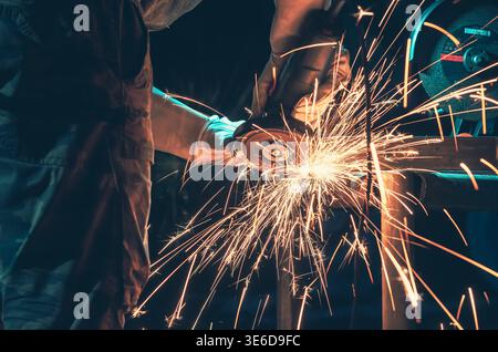 Goldene Funken beim Polieren von Metall in der Werkstatt. Dramatische Beleuchtung und unscharfer dunkler Hintergrund betonen Energie, Bewegung und industrielle Atmosphäre. Stockfoto