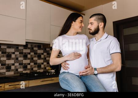 Schwangere Paare. Glückliche Familie. Schwangere Frau mit Ehemann in der Küche. Stockfoto