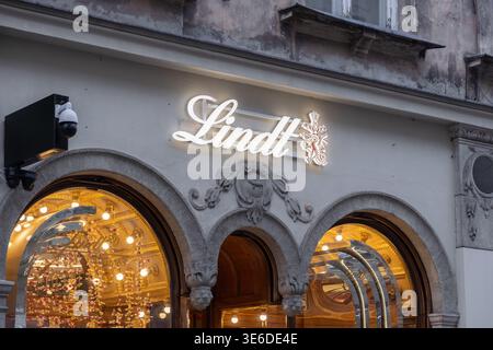 Krakau, Polen - 1. Dezember 2025: Lindts leuchtendes Neonschild beleuchtet ein verziertes altes Stadtgebäude und lädt Gäste zu einem luxuriösen Schokoladenkonfekt ein Stockfoto