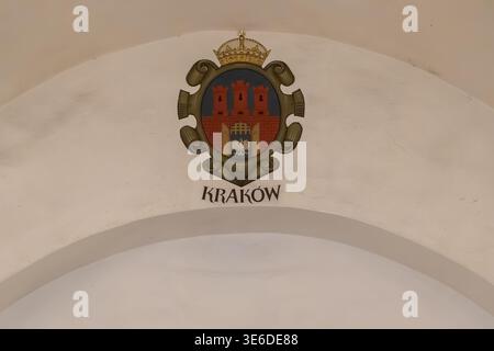 Krakau, Polen - 1. Dezember 2025: Detaillierte Ansicht des historischen Krakauer Wappens mit einem gekrönten Adler und Stadtmauern, gemalt auf einem Steinbogen Stockfoto