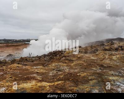 Beschädigter Holzweg in den Gunnuhver Hot Springs. Aktives geothermisches Gebiet mit vulkanischen Kratern, Schlammbecken und Dampfdüsen. Bewölkter und regnerischer Tag. Stockfoto