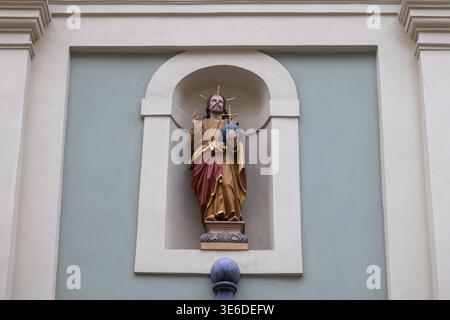 Krakau, Polen - 1. Dezember 2025: Jesus Christus-Statue mit einem Halo, das ein Globus-Kreuz hält, in einer architektonischen Nische, die spirituellen Glauben vermittelt, hingebungsvoll Stockfoto