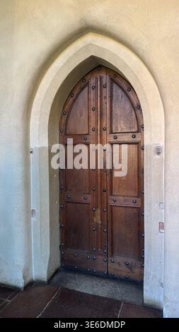 Mittelalterliche Holztür mit Metallstollen in spitzem gotischem Bogen im Schloss Malbork in Polen. Architektur, Geschichte und Kulturerbe. Stockfoto