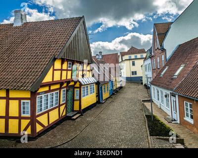 Eine ruhige Kopfsteinpflasterstraße, gesäumt von bunten Fachwerkhäusern, steilen Ziegeldächern und traditionellen Fassaden in einem bezaubernden historischen europäischen Dorf Stockfoto