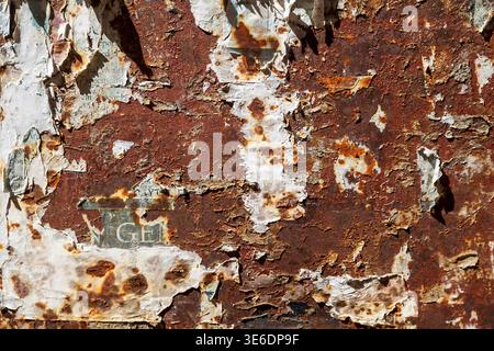 Gerissene Poster auf rostiger Metalloberfläche mit Schmirgelstruktur. Stockfoto