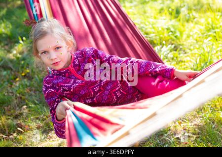 Kind genießt die Zeit in der Hängematte während des Sonnentages im Park Stockfoto