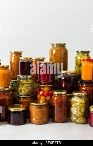 Canning ist eine häufige Aktivität in der Küche, da die Theke mit Gemüse und Obst gefüllte Gläser säumen. Diese Praxis hilft dabei, Lebensmittel für den Gewinn zu bewahren Stockfoto
