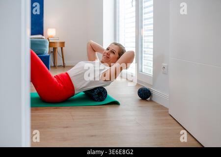 Draufsicht einer Frau mittleren Alters, die zu Hause Sport treibt. Stockfoto