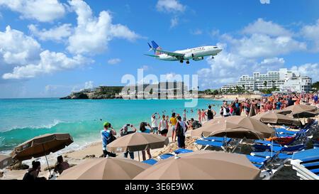 Das Flugzeug der amerikanischen Fluggesellschaft United fliegt über den Köpfen der Touristen am einzigartigen und gefährlichen Maho Beach in Sint Maarten, der Karibik. Stockfoto