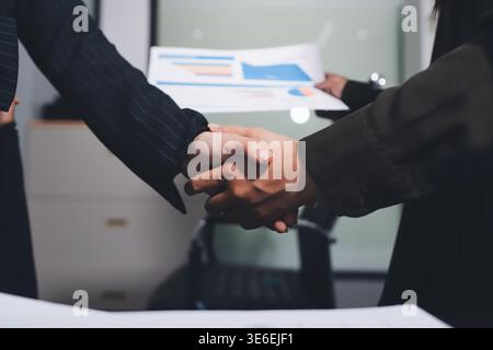 Junge Geschäftsleute, die sich im Büro die Hände schütteln. Erfolgreiche Besprechung wird beendet. Drei Personen. Breitbild-Panorama Stockfoto