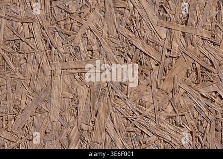 Die Holzspanplatten-Textur zeichnet sich durch eine Holzverbundoberfläche aus, die sich ideal für den Bau eignet. Die strukturierte Oberfläche hebt natürliche Muster bei Tageslicht hervor. Stockfoto