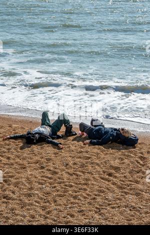 Mann und Frau liegen zusammen an einem Kiesstrand in Ventnor auf der isle of wight an einem warmen Frühlingstag. Stockfoto