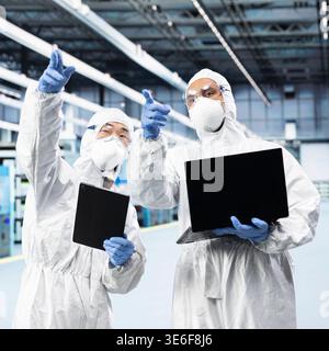 Multiethnisches Ingenieurteam arbeitet in der Mikroelektronik-Produktionsfabrik zusammen und überwacht die Infrastruktur. Microchips-Kollegen, die Teamarbeit leisten, verfolgen Leiterplatten-Fertigungschargen mit Geräten Stockfoto