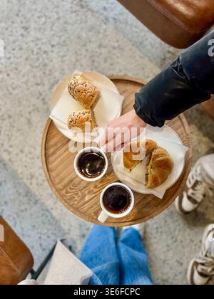 Blick von oben auf ein gemütliches Café mit zwei Tassen heißem Kaffee und frischen Bagel-Sandwiches auf Tellern, serviert zum Frühstück oder Brunch mit warmen, zwanglosen atmos Stockfoto