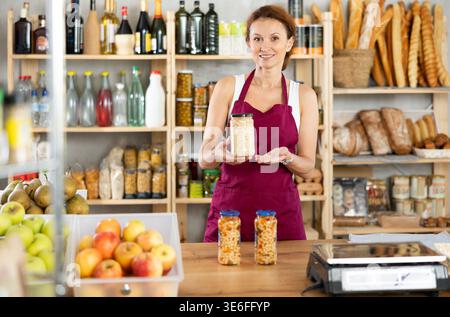 Eine Erwachsene Verkäuferin bietet Bohnen im Lebensmittelgeschäft an Stockfoto