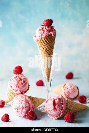Eis mit Himbeere im Waffelkegel auf blauem Hintergrund Stockfoto