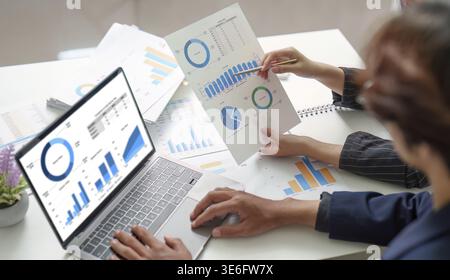 Zwei Fachleute haben gemeinsam Finanzdaten analysiert, indem sie Berichte und ein Notebook nutzen, um ihre Diskussion zu verbessern Stockfoto