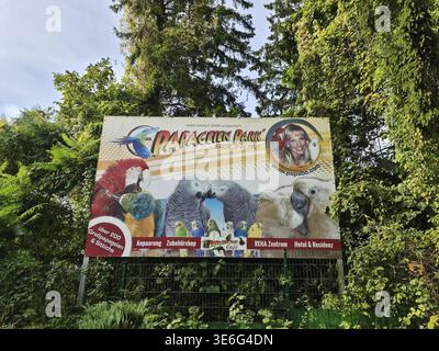 Bochum, Deutschland - 25. September 2025: Papageien Park Bochum Werbetafeln, die verschiedene Papageienarten im grünen Laub bewerben Stockfoto