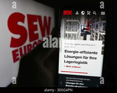 Stuttgart, Deutschland - 08-05-2024: Person mit Handy und Webseite des deutschen Ingenieurbüros SEW-Eurodrive GmbH Co. KG vor dem Logo. Fokus Stockfoto