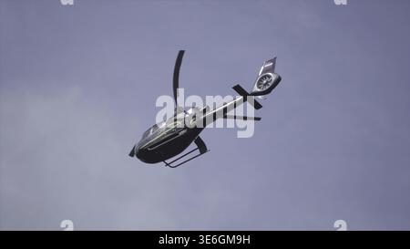 Hubschrauber am bewölkten Himmel mit Blitz. Hubschrauber Von Unten, Der Durch Den Bewölkten Himmel Fliegt. Hubschrauber schwebt gegen hellen, sonnigen und bewölkten Himmel Stockfoto
