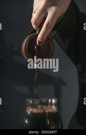 Ein von Hand gegossener frisch gebrühter Kaffee, der seinen reichen Fluss in einen Glasbehälter zeigt und Wärme einlädt Stockfoto