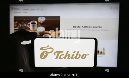 Stuttgart, Deutschland - 08.07.2024: Person mit Mobiltelefon mit Logo des deutschen Kaffeehändler Tchibo GmbH vor der Business-Website. Konzentrieren Sie sich auf Stockfoto