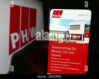Stuttgart, Deutschland - 08-05-2024: Person mit Handy und Webseite des deutschen Fleischverarbeitungsunternehmens Lohmann Co. AG (PHW-Gruppe) mit Logo. Fokus Stockfoto