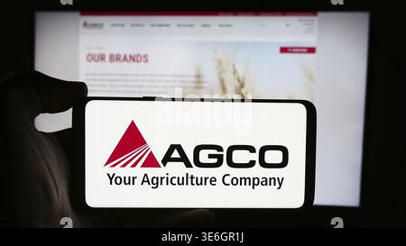 Stuttgart, Deutschland - 18.08.2024: Person, die ein Mobiltelefon mit dem Logo des US-amerikanischen Landmaschinenunternehmens AGCO Corporation vor der Webseite hält Stockfoto