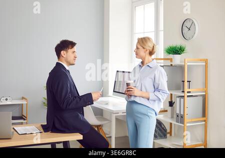 Zwei Kollegen führen ein freundliches Gespräch in ruhiger Atmosphäre am Arbeitsplatz im Büro. Stockfoto