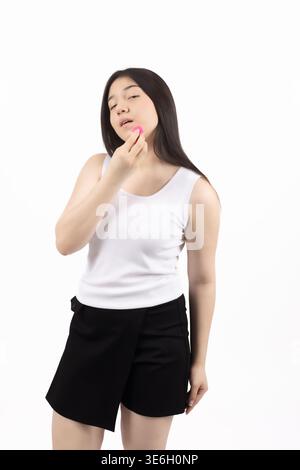 Eine junge Frau in weißem Oberteil, die ihr Kinn nachdenklich berührt Stockfoto