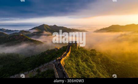 Goldener Sonnenaufgang, der die Chinesische Mauer von Jinshanling über nebeligen Bergkämmen in Nordchina beleuchtet. Stockfoto