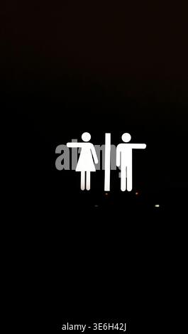 Minimalistisches leuchtendes WC-Richtungsschild mit kreativen Humor-Piktogrammen, die in entgegengesetzte Richtungen zeigen. Isoliert auf schwarzem Hintergrund. Pe Stockfoto