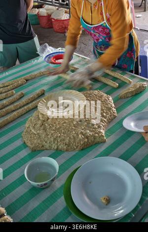 Eine Person bereitet ein traditionelles vietnamesisches Gericht zu und formt Zutaten auf einer gestreiften Tischdecke Stockfoto