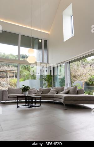 Geschwungene graue Sitzecke in modernem Zuhause, mit Kissen und schwarzem Couchtisch Stockfoto