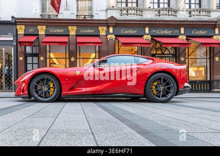Der rote Ferrari parkte auf einer Stadtstraße vor einer Luxusboutique. London, UK, 28. August 2023 Stockfoto