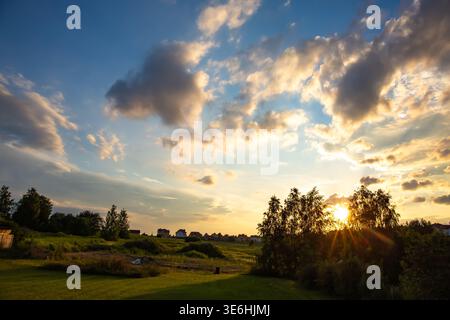 Eine lebendige Weitwinkelaufnahme fängt einen teilweise bewölkten Himmel ein, der von tiefem Blau in helle Farbtöne übergeht, wobei die Sonne die Wolken in warmem Gelb beleuchtet Stockfoto