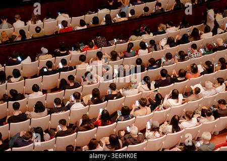 Taipeh, Taiwan - 13. April 2024: Luftaufnahme eines mehrstufigen Publikums im National Theater, das Telefone und Broschüren durchsucht, bevor der Vorhang aufgeht. Stockfoto