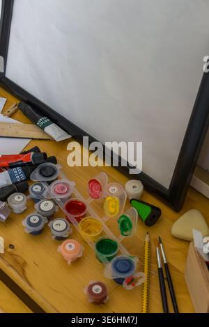 Acrylfarben und nummerierte Farbtöpfe auf Holztisch. DIY-Malset, kreatives Hobby, farbenfrohes Kunstkonzept. Stockfoto