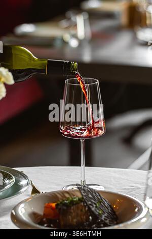 Rotwein ins Glas im Restaurant gießen Stockfoto