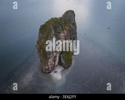Aus der Vogelperspektive auf eine majestätische Kalksteininsel, die sich aus dem türkisfarbenen Meer erhebt, mit ihren Klippen, die von üppigem Grün gekrönt sind, Krabi, Thailand. Stockfoto