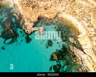 In der Blue Lagoon, Comino, Malta, treffen Sie aus der Vogelperspektive auf schroffe Klippen in einem faszinierenden Tanz aus Licht und Schatten. Stockfoto