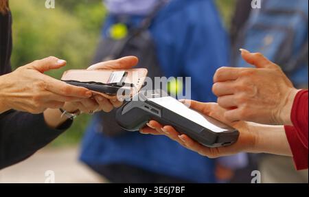 Nahaufnahme eines Kunden, der eine kontaktlose Smartphone-Zahlung beim Outdoor-Botschaftsfestival in Prag Dejvice tätigt. Perfekt für moderne Finanzen, bargeldlos Stockfoto