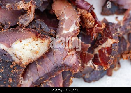 Makroaufnahme von Rindfleisch Biltong mit detaillierter Textur, Fettmarmorierung und Gewürzbeschichtung. Ideal für Hintergründe mit Lebensmittelstruktur, Protein-Snack-Conce Stockfoto